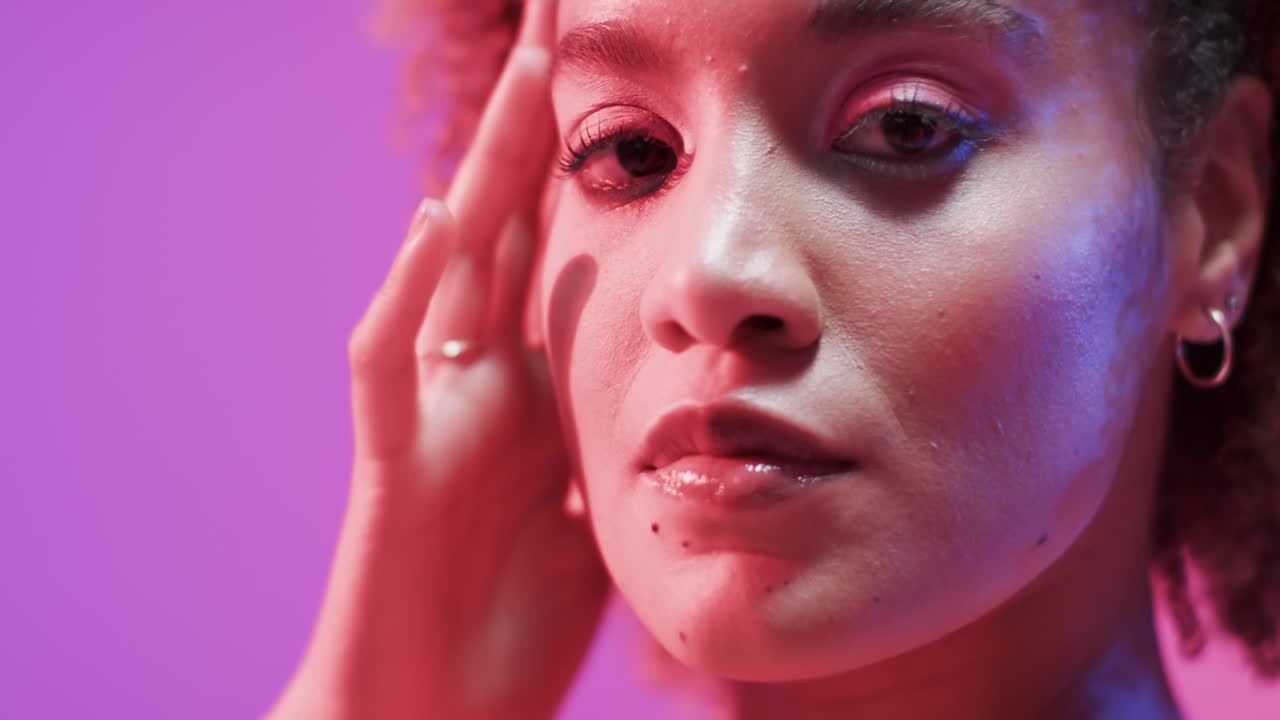 mujer biracial con cabello oscuro en luz azul y rosa, cámara lenta