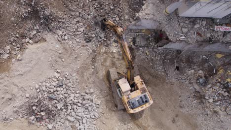 Gelbe-Baggermeißel-Aus-Der-Luft-Von-Oben-Nach-Unten-Auf-Stein-Auf-Einer-Baustelle