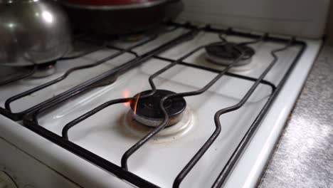 burner gas stove is lit by a woman's hand with a lighter