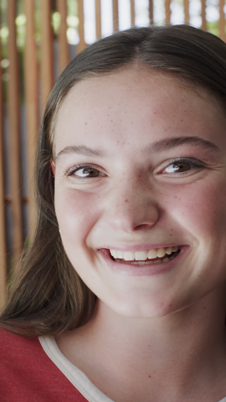 Vertical video of portrait of happy caucasian teenage girl in slow motion