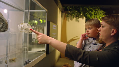 mother showing animal bones to toddler daughter in a natural history museum