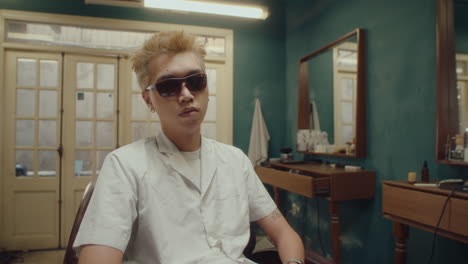 cool asian barber posing for camera in vintage barbershop