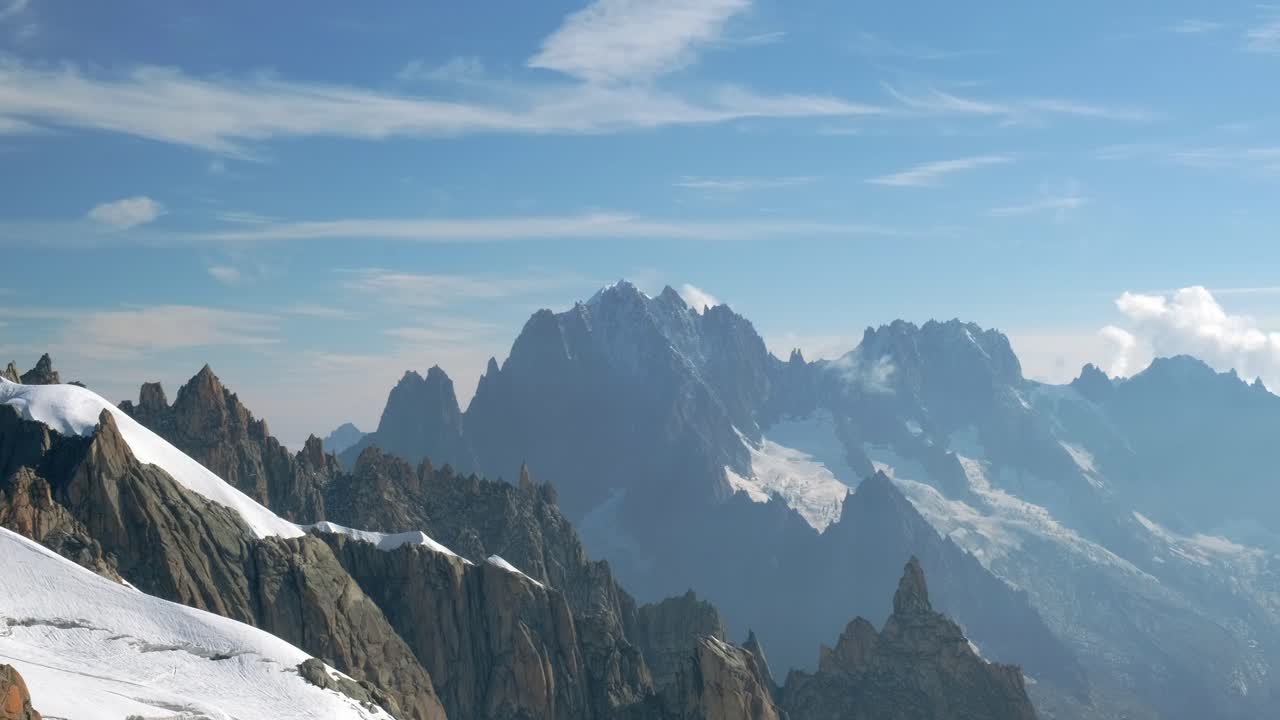 Fransız Alpleri'ndeki Chamonix Vadisi'nde, mavi gökyüzüyle güneşli bir günde karlı dağların panoramik görünümü.