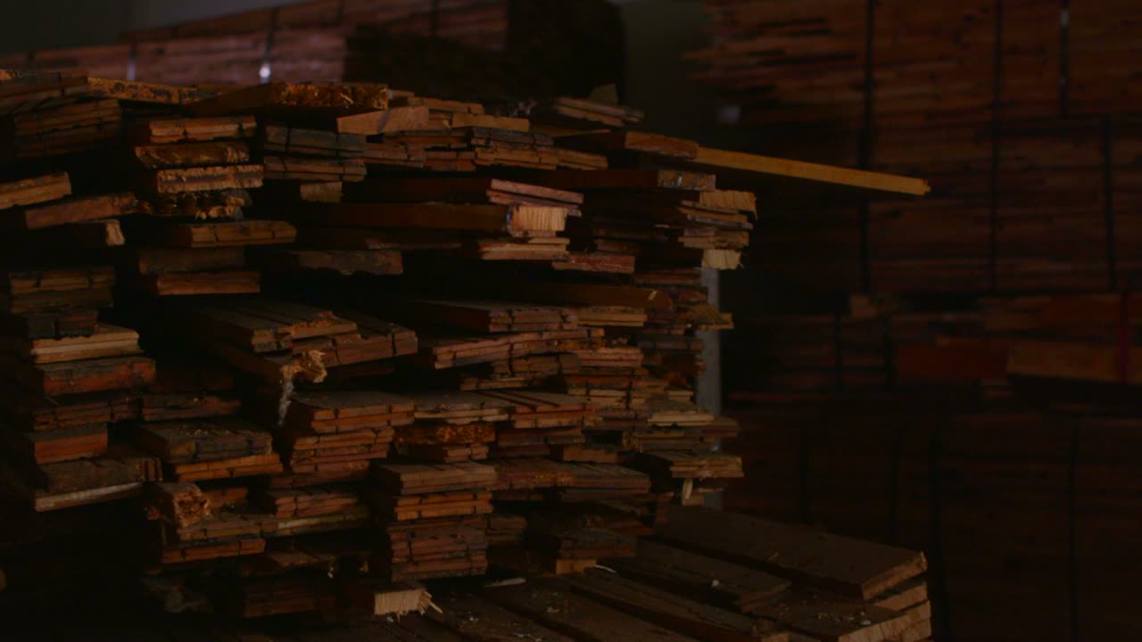 pan a la derecha a través de tablones de madera apilados en un taller 1