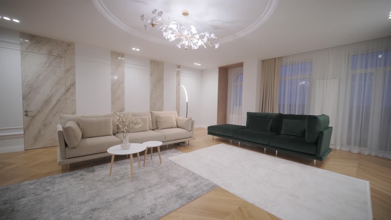 espaciosa sala de estar con sofás elegantes, columnas de mármol y un distintivo candelabro floral, bañado en luz suave