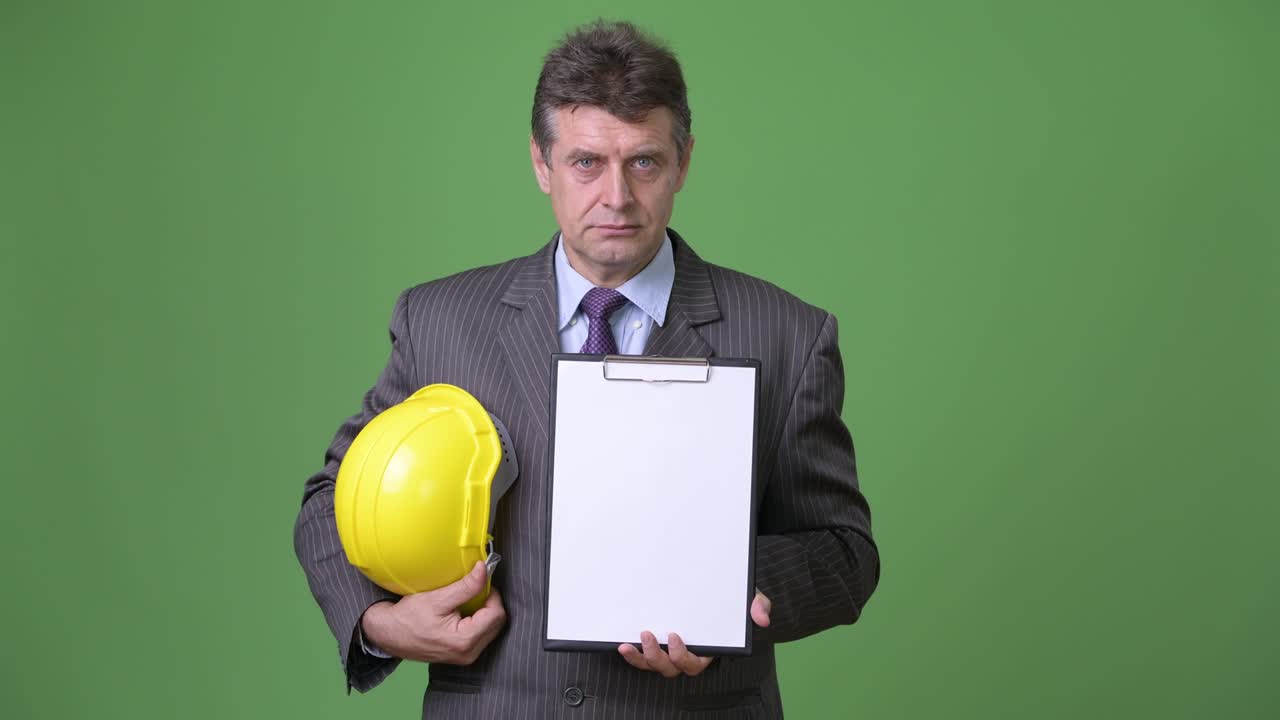 hombre de negocios maduro y guapo contra un fondo verde