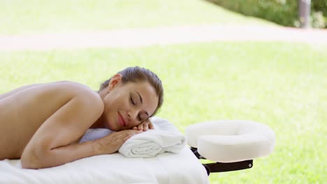 naked woman on spa table closes her eyes