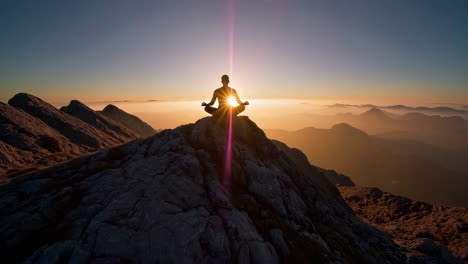 person meditating on mountain peak at sunrise/sunset