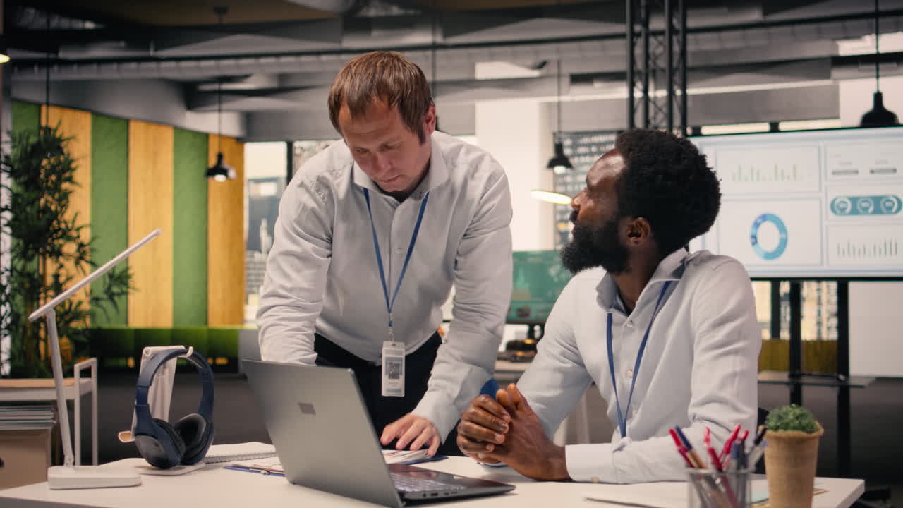 Diverse corporate office scene with team collaboration around laptop