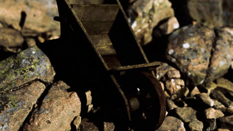 old wheelbarrow abandoned on rocky terrain during bright daylight
