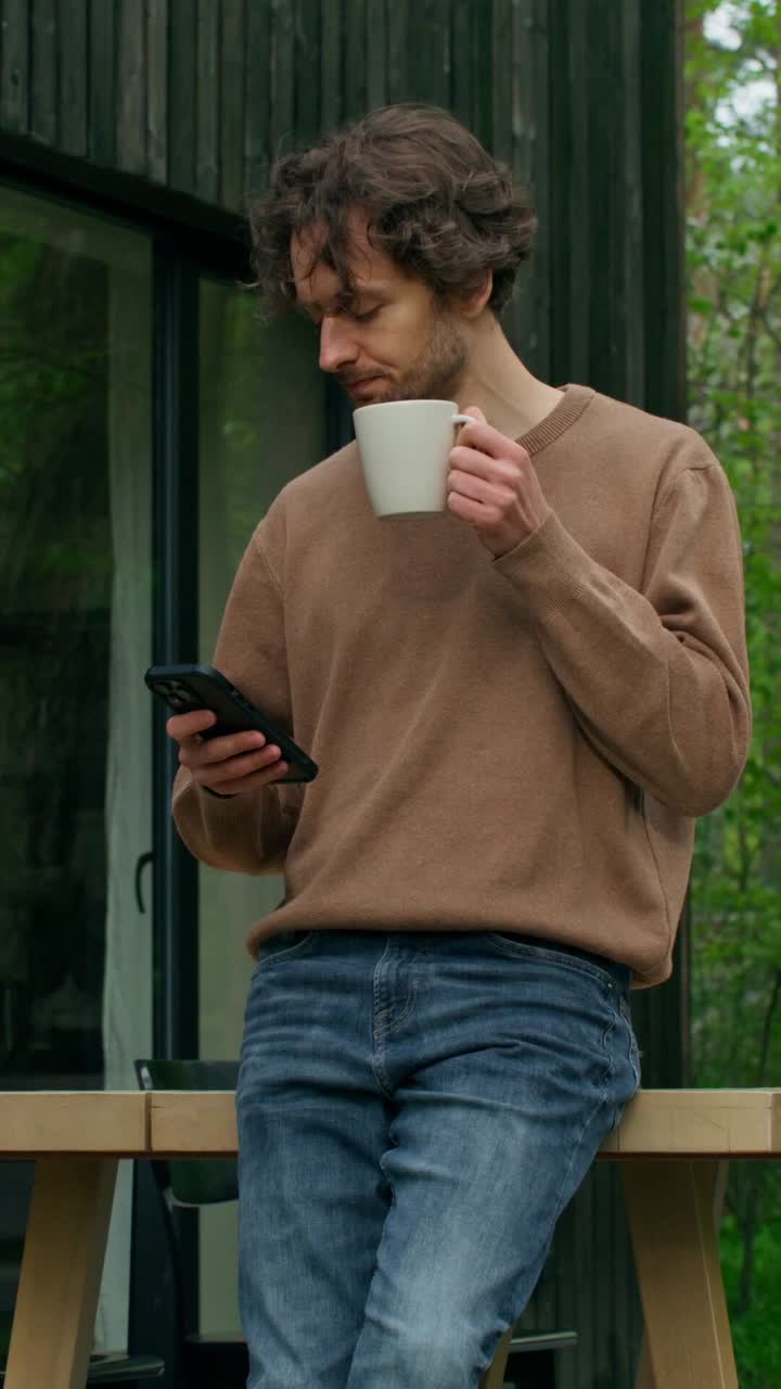 커피와 전화로 야외에서 휴식을 취하는 남자