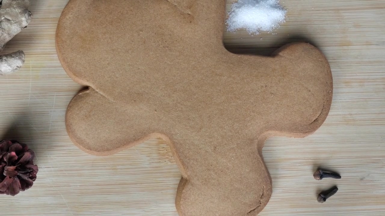 Gingerbread cookie ingredients on wooden board with big gingerbread cookie next to it