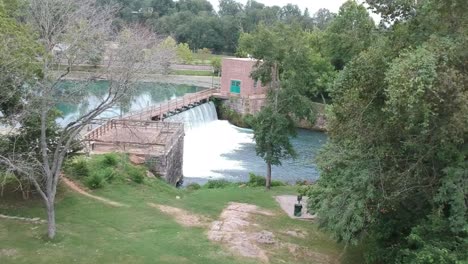 flying thru the trees approaching a waterfall dam drone angle