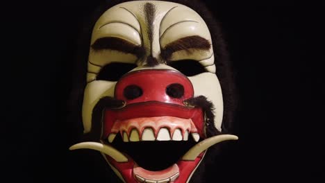 closeup theater mask of demoniac pig, angry animal, inifinite black background, bali indonesia, topeng art and cultural tradition