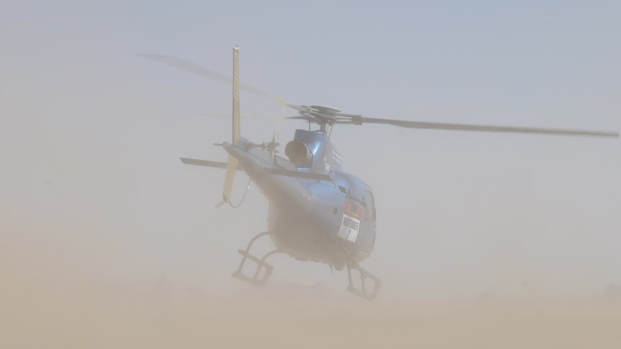 lugar extremadamente polvoriento con despegue de helicóptero azul y unidades de automóviles por