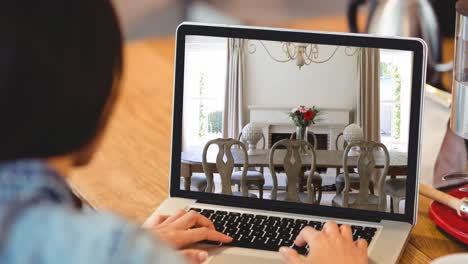 mujer usando una computadora portátil con interiores de comedor modernos mostrados en la pantalla