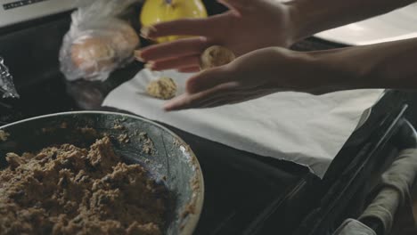 baker's hands shaping cookie dough and placing in a tray with parchment paper - close up