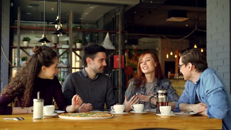 una joven alegre y atractiva está contando una historia divertida a sus amigas en el almuerzo en un café, la gente está riendo y discutiendo. comunicación y concepto de comer fuera.
