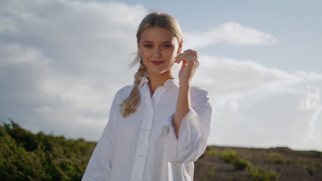 Donna raggiante che cammina da sola sulla cima di una collina, primo piano. Ragazza sorridente che cammina nella natura della valle.