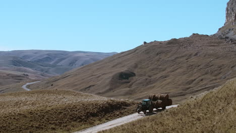 tractor transporting hay bales through a scenic mountain valley