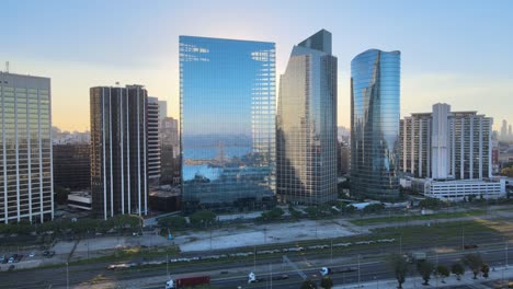 aerial of paseo del bajo highway near window glass puerto madero skyscrapers at golden hour, buenos aires