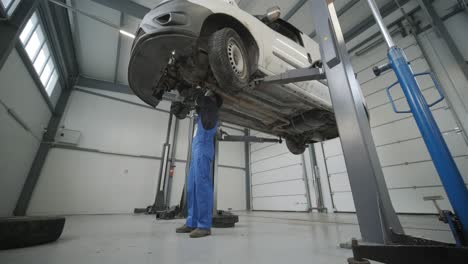 auto mechanic working underneath car lifting machine at the garage. auto repair shop. car service, repair.