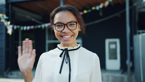 young woman waving hello outside
