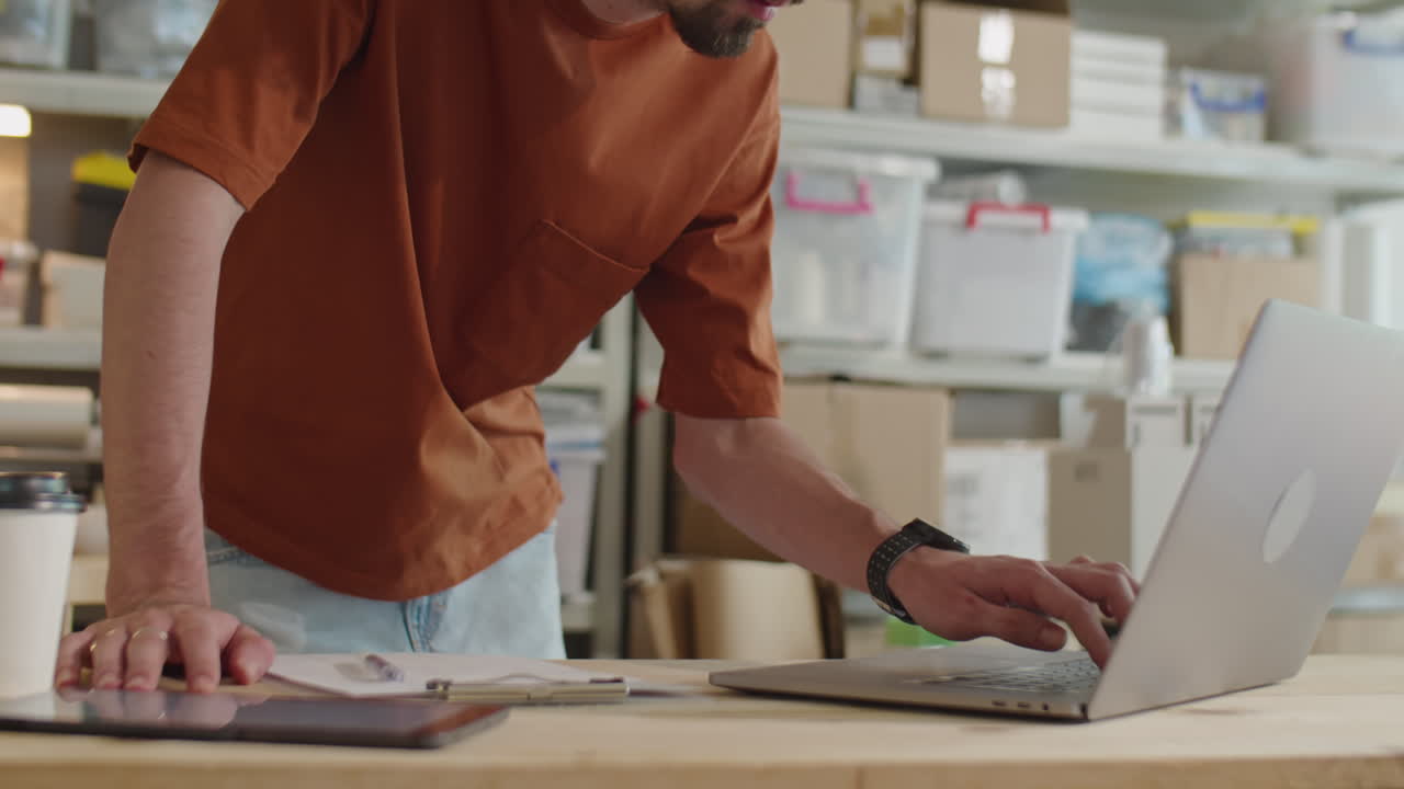 Man Working on Laptop in Office of Delivery Service Company