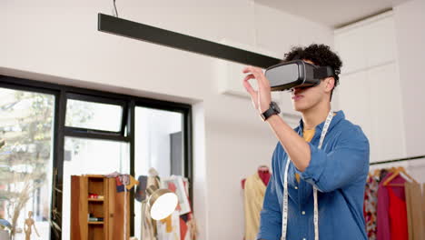 biracial male fashion designer using virtual reality headset in studio, slow motion