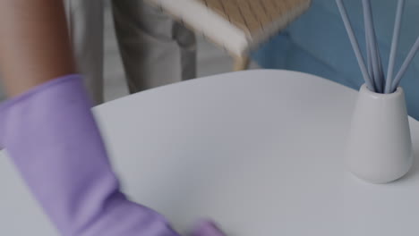 woman cleaning a table with purple gloves