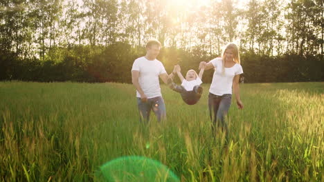 mother father and son walk in the field with spikes in white t-shirts and jeans fun swinging it on his hands