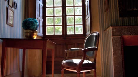 slow establishing shot of a small office desk and chair in front of a hatched window