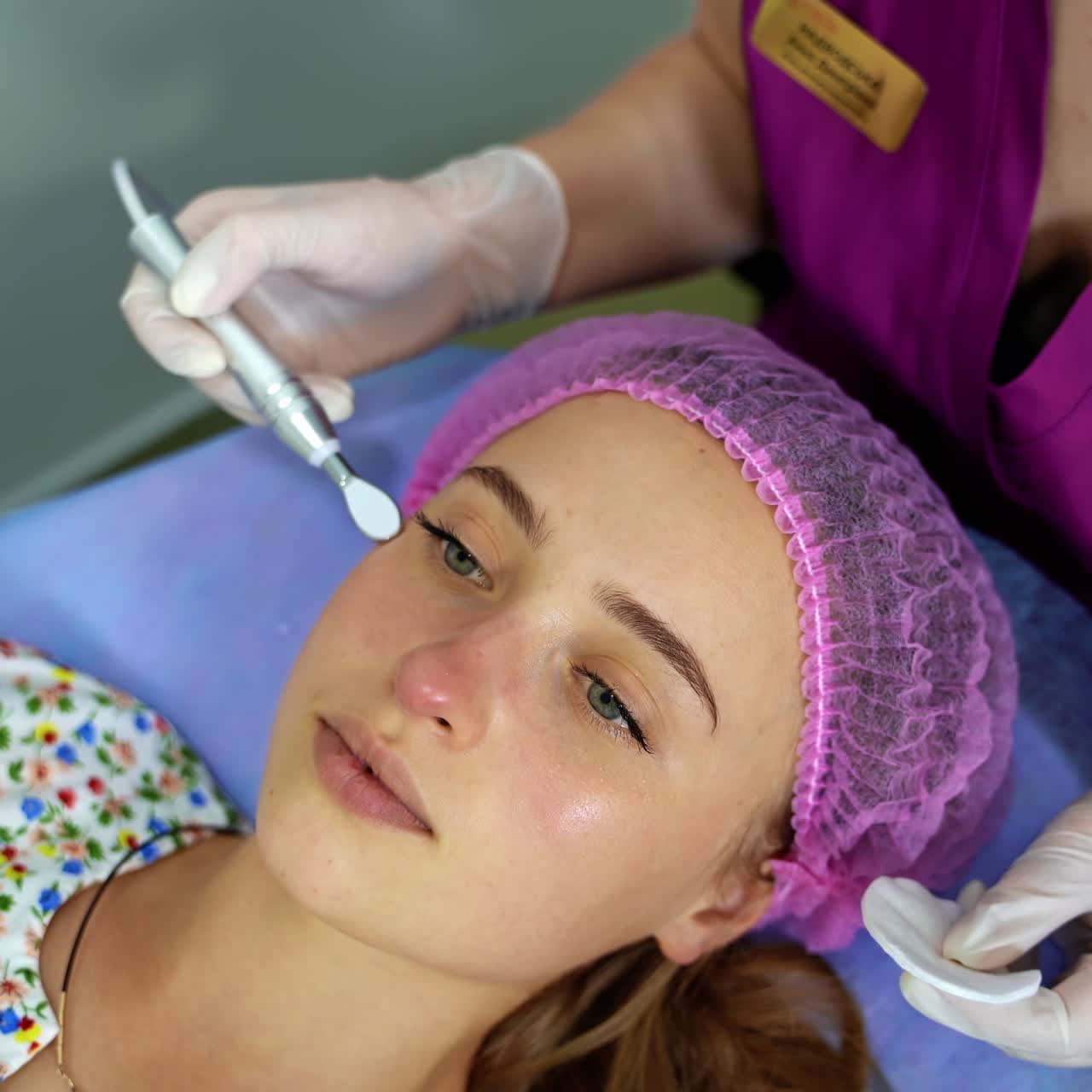 Cosmetology. Woman in clinic receiving stimulating electric facial treatment. Closeup of young female face during microcurrent therapy
