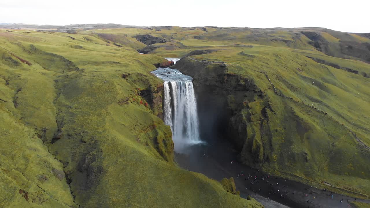 turistas de pie debajo de la cascada de skogafoss disfrutando de su famosa vista