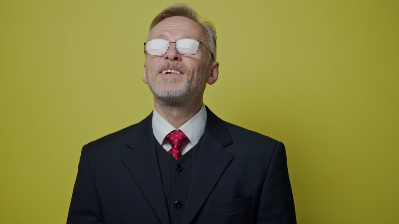 Portrait of smiling businessman on yellow background. Mature man in costume with tie talking and looking on camera.