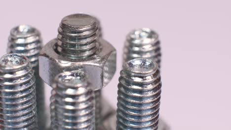 rotating group of galvanized metallic screws close-up. steinless steel bolts isolated on white background.