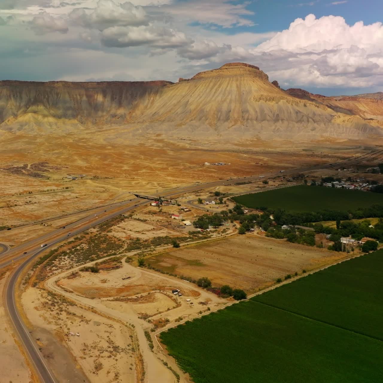 Cittadina splendida e campi verdi vicino alla pianura desertica e alla montagna del canyon. Scenario incredibile della natura del Colorado sullo sfondo di cieli blu e nuvole bianche