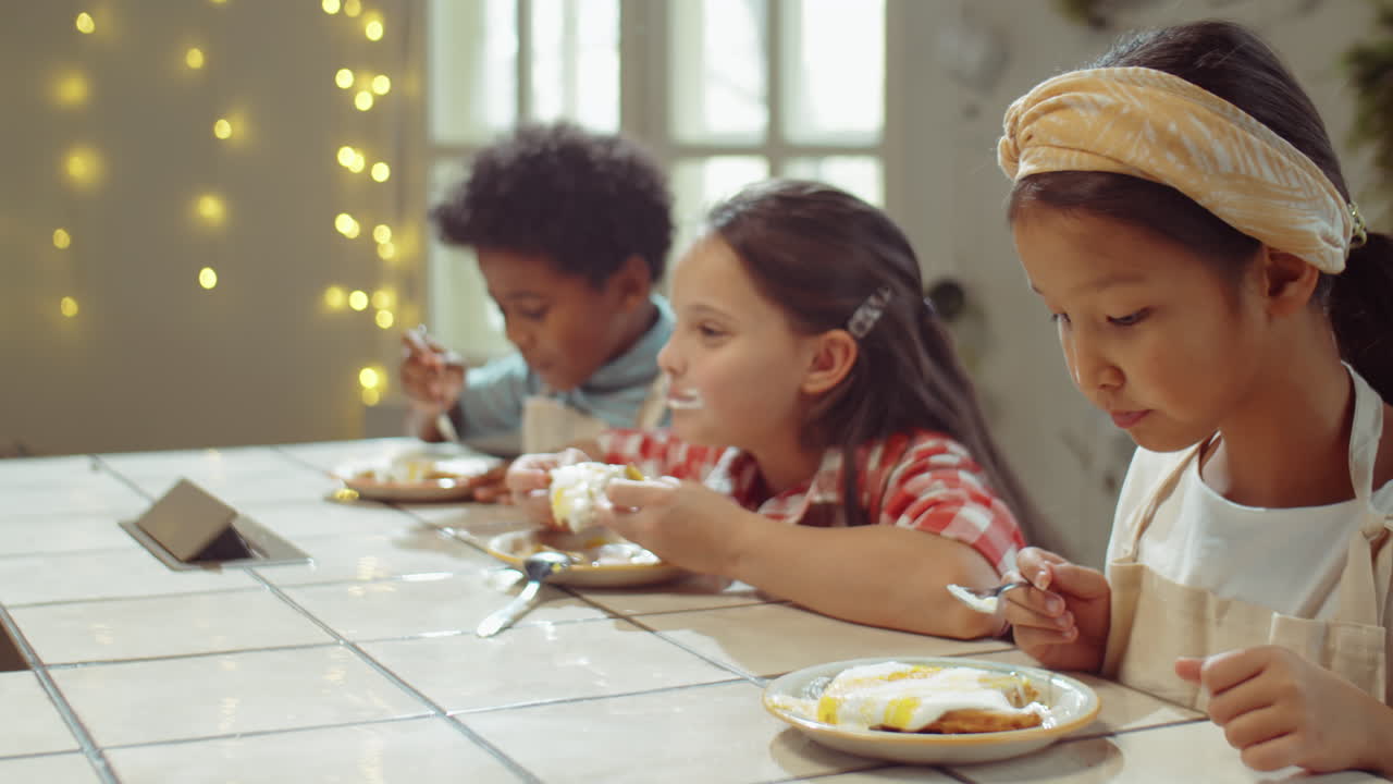 Bambini che mangiano waffle dolci durante una lezione di cucina