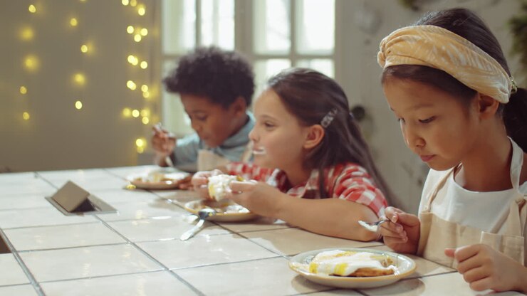 Bambini che mangiano waffle dolci durante una lezione di cucina