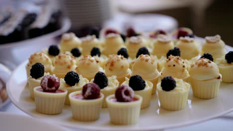 Plastic-glove-hand-places-sweet-berry-treat-on-dessert-buffet-table,-close-up