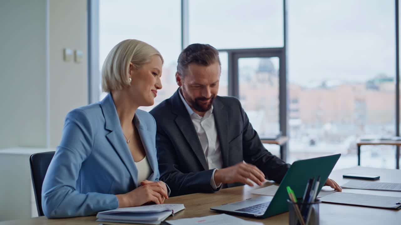 Coworkers talking virtual meeting looking laptop webcam in light office closeup