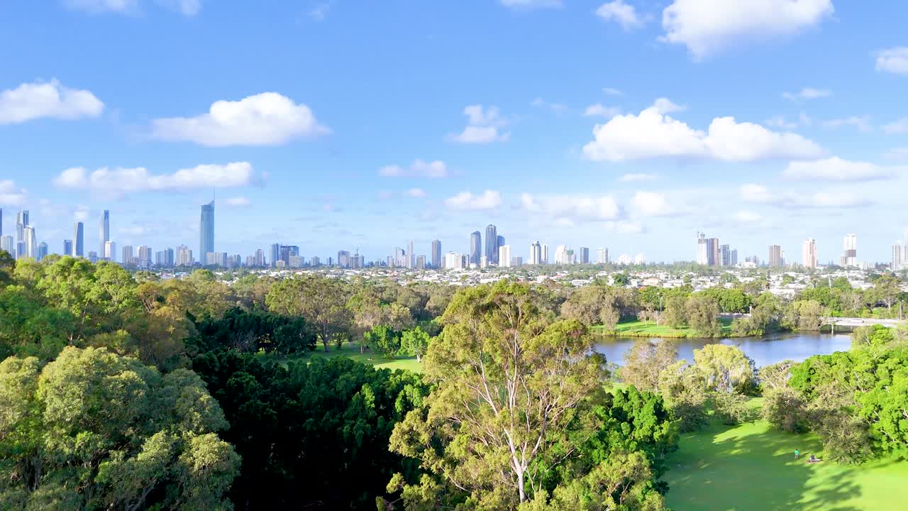 Drone footage captures Gold Coast's vibrant greenery and skyline under clear blue skies, showcasing urban and natural harmony