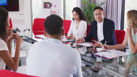 Senior-businessman-discussing-with-young-business-people-in-meeting-room-in-modern-office