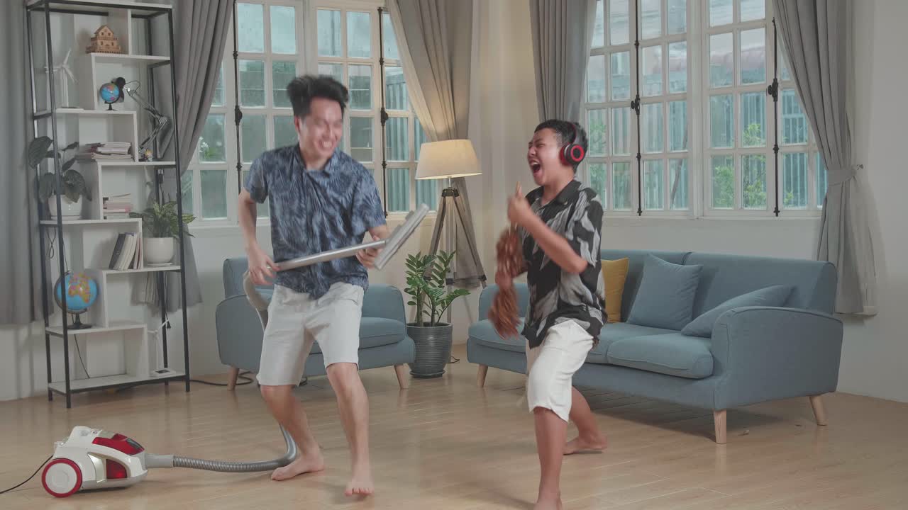 Cheerful Young Asian Father And Son Cleaning Up They Home And Singing