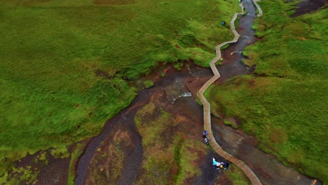 turistas en el valle de reykjadakur en islandia famoso por su río caliente con pasarela de madera