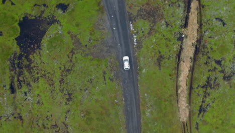 aerial top down of white car on muddy dirt road with potholes