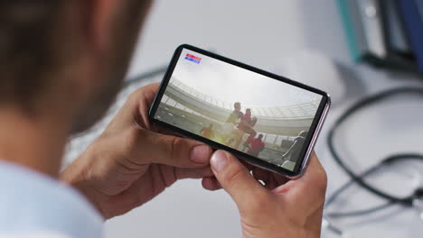 composite of male doctor watching rugby match on smartphone