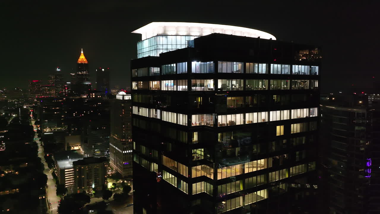 órbita elevada disparada alrededor de un moderno edificio de oficinas de gran altura con ventanas iluminadas