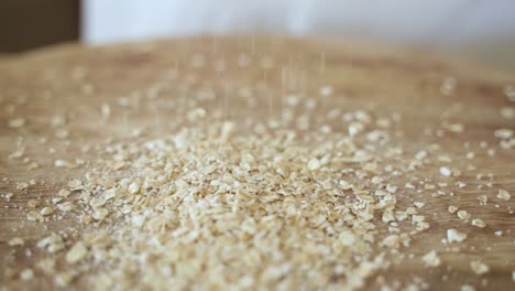 oat flakes fall into pile on wooden tablle, slow motion close up with copy space