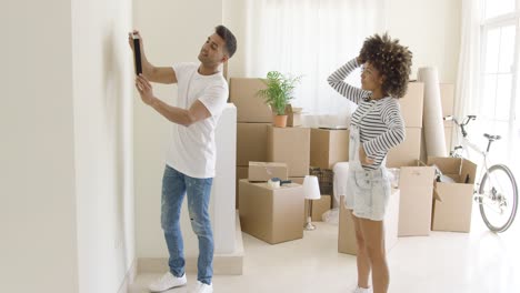 Young-couple-hanging-pictures-in-their-new-home